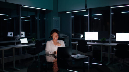 Happy African-American businesswoman work on computer late in office