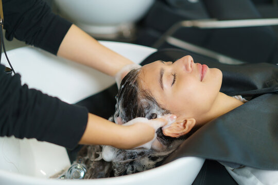 hairdresser is applying shampoo and massaging hair of a customer. Woman having her hair washed in a hairdressing salon..