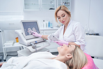 Dermatologist adjusting treatment setting for patient before cosmetic procedure