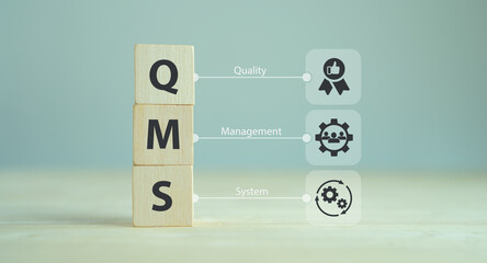QMS, Quality management system concept. Formalized system for achieving quality policies and objectives.  ISO 9001 standard.  Wooden cubes with abbreviation of QMS and symbols on smart background.