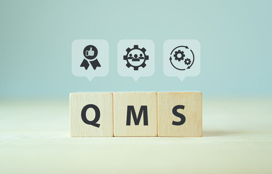 QMS, Quality management system concept. Formalized system for achieving quality policies and objectives.  ISO 9001 standard.  Wooden cubes with abbreviation of QMS and symbols on smart background.