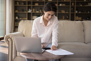 Happy satisfied young homeowner woman calculating taxes, budget, costs, paying bills, insurance,...