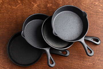 pile of cast iron skillets on wood table