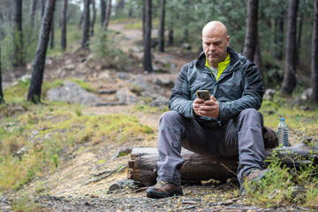 Hiker man using phone in lonely forest.
