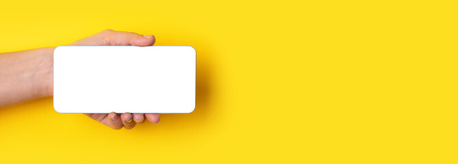 Obraz premium hand holding smartphone with white screen over yellow background, panoramic layout