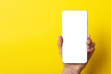 Smartphone in female hand over yellow background, layout image