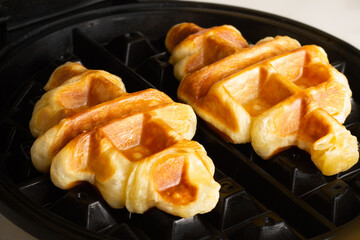 Crisp and golden croffles, freshly baked in a waffle maker, highlighting their unique texture and delightful aroma