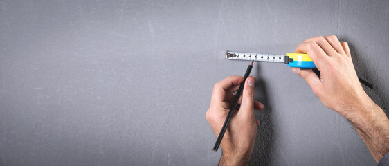 Measuring tape and pencil marking with a wall.