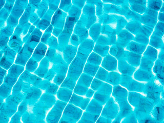 Fototapeta na wymiar Clean and clear blue water surface with movement wave shining with the light on the swimming pool background. Empty blank space for summer background, vacation time, holiday concept.