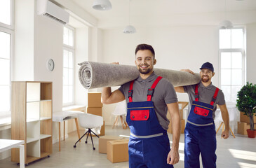 Smiling young male movers carrying carpet unload goods in client home or office. Happy removal...