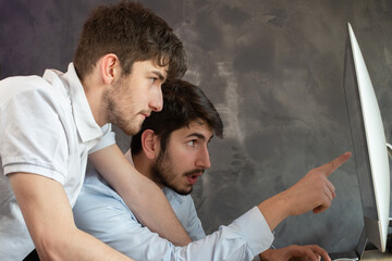 deux jeunes hommes d'affaire ou employés de bureau travaillent ensemble devant un ordinateur. Ils...