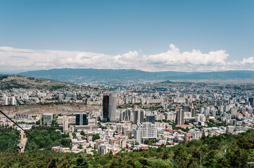 Fototapeta premium Top view from the highest point to the new and old houses, skyscrapers, city, town, and most famous park in Tbilisi is the capital of Georgia.