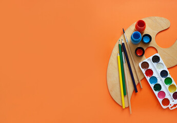 various tools for painting: brushes, paints wooden easel. flatley style on orange background. copy space,place for text art concept, learning to draw. baner style