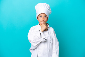 Little chef boy isolated on blue background having doubts and thinking