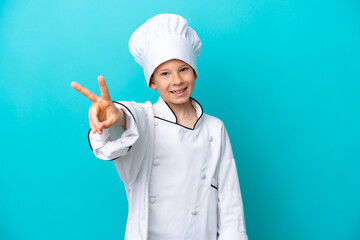 Little chef boy isolated on blue background smiling and showing victory sign