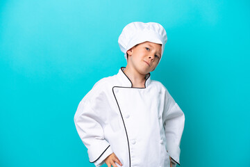 Little chef boy isolated on blue background suffering from backache for having made an effort