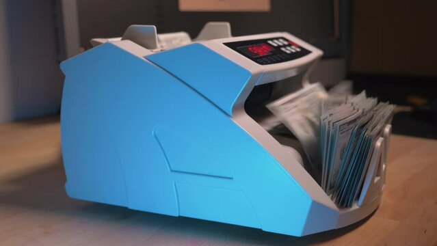 Currency counting machine counting 100 dollar banknotes. Side view of money counting equipment