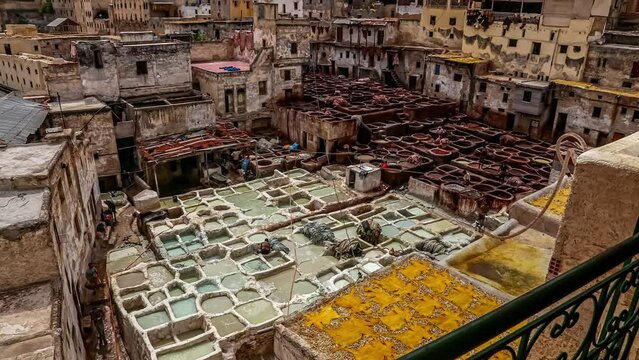 Overview of Chouwara traditional leather tannery in timelapse in Old Fez, Morocco. View of vats for tanning and dyeing leather hides at daytime.