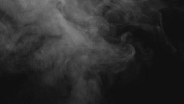 Abstract smoke or steam is rising and floating in the air on a black background.