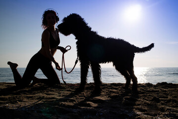 Backlight of young woman with her dog