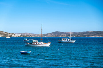Fototapeta na wymiar Milos Greek island, Cyclades. Fishing boat moored in open Aegean calm sea, blue sky background.