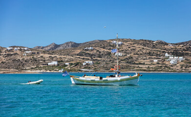 Naklejka na ściany i meble Fishing and inflatable boat moored in Aegean sea blue sky background. Paros Greek island, Cyclades