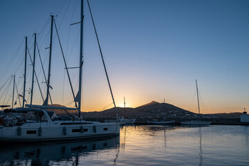Fototapeta na wymiar Sunset over Paros Greek island, Cyclades. Yacht and boat moored at port dock blue sky background.