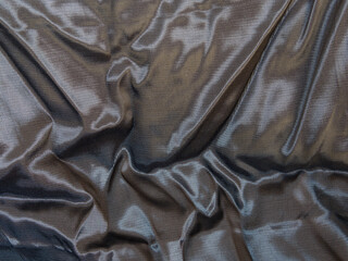 Abstract grey silk background, the fabric is covered with waves. Black background is a luxurious wave texture fabric. Crumpled silver metallized fabric with regular pattern. Background, texture