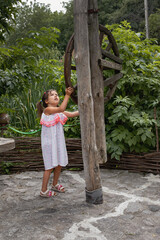 portrait of a little girl in a dress near an old wooden well. Happy childhood concept. Vacation