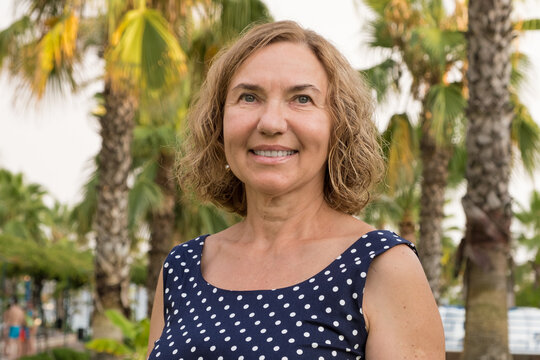 Portrait of a mature woman 50-60 years old against the backdrop of palm trees