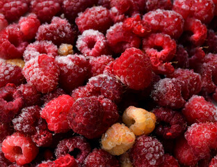 Frozen ripe berries of red and yellow raspberries were taken out of the freezer. Ice crystals on berries. A delicious memory of summer. Preservation of the harvest. Berry background
