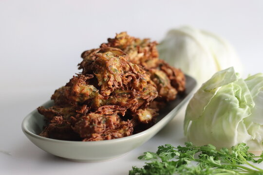 Indian cabbage fritters. Made with shredded cabbage, chickpea flour, green chilies, coriander leaves and spices. Deep fried in vegetable oil. Commonly known as cabbage pakoda