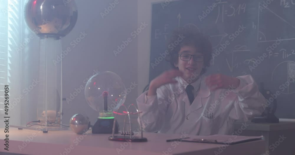 Wall mural schoolboy experimenting in physics class. young student doing physics experiment in the classroom