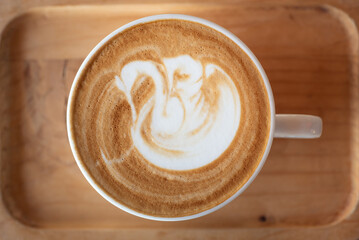 Cup of hot latte art coffee on wooden table