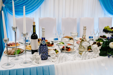 Festive table, arch, stands decorated with composition of flowers and greenery, candles in the banquet hall. Table newlyweds in the banquet area on wedding party. Stylish blue wedding.