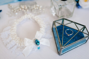 Fototapeta na wymiar Diamond wedding ring. Engagement. Woman's garter on a white background. Bride accessories. Stylish blue wedding.