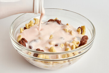 Yogurt is poured into a transparent bowl of granola on a white background. Healthy food. Baby food.