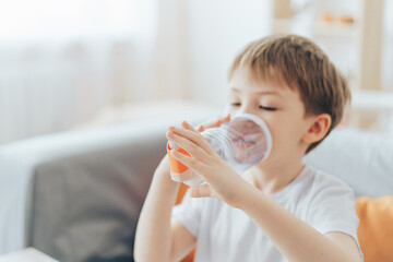 Little boy inhales medicine through homemade spacer.