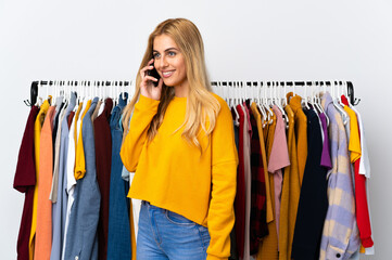 Young Uruguayan blonde woman in a clothing store keeping a conversation with the mobile phone with someone