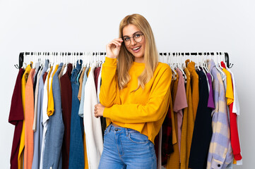 Young Uruguayan blonde woman in a clothing store with glasses and happy