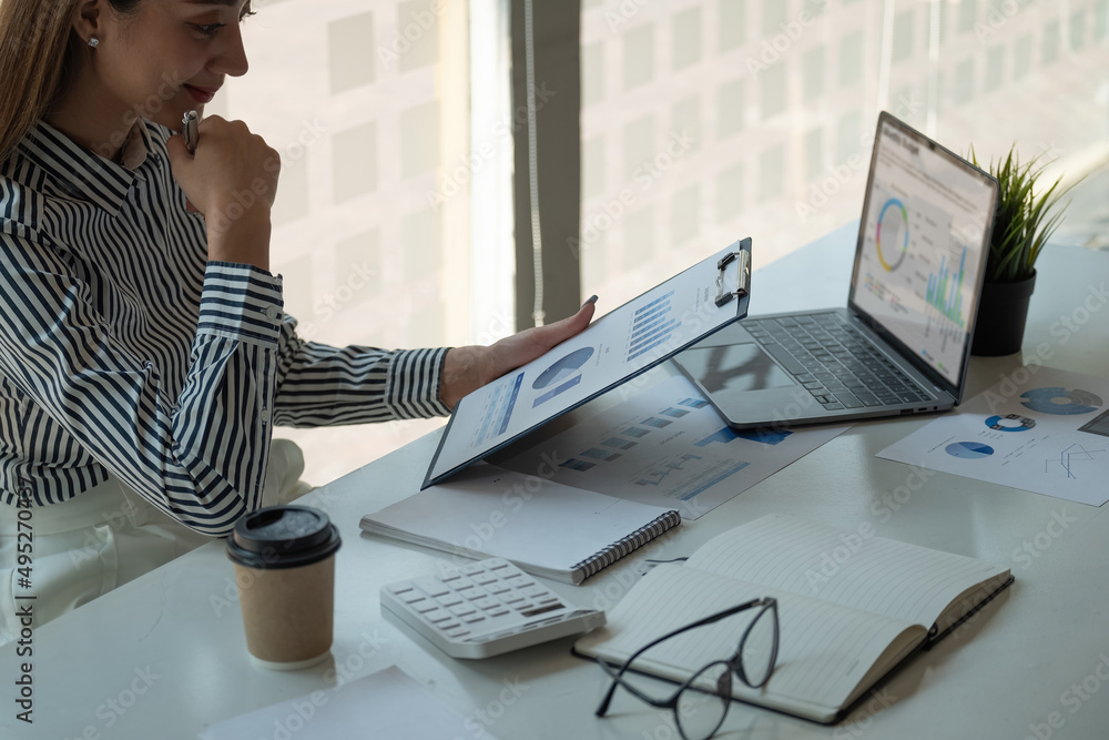 Aufkleber businesswoman analysis turnover with graph chart report and use laptop computer for analysis data