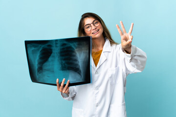 Professional traumatologist isolated on blue background happy and counting three with fingers