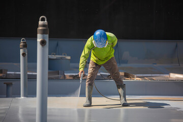 A male worker holding an industrial spray gun used for roof plate tank surface on steel industrial...