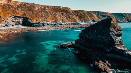 Rocks off the ocean coast line with turquoise water and dramatic cliffs Aerial view