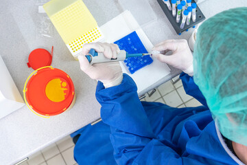 Medical lab scientists in laboratory using Air displacement micro pipettes filling a colorless...