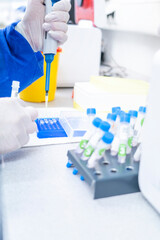 Hand in laboratory Air displacement micro pipettes filling a colorless reaction tube.