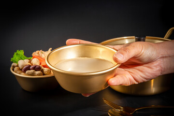 Makgeolli rice wine is a Korean fermented alcoholic beverage traditional drinks. 
Korean alcoholic drink (Makgeolli) in a traditional Korean gold liquor bowl with snack on Black background. 