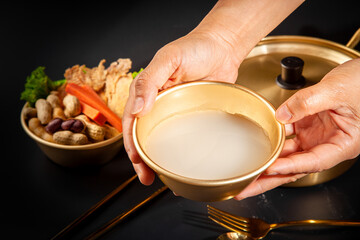 Makgeolli rice wine is a Korean fermented alcoholic beverage traditional drinks. 
Korean alcoholic drink (Makgeolli) in a traditional Korean gold liquor bowl with snack on Black background. 