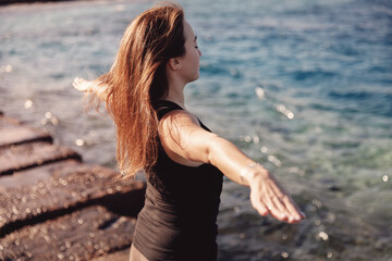 Fototapeta na wymiar Concept woman power energy healthy life. Girl practices yoga on background of sea, wind blows hair