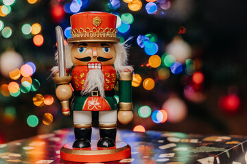 Nutcracker wooden toy on the background of festive Christmas lights. Nutcracker figurine. Bokeh....